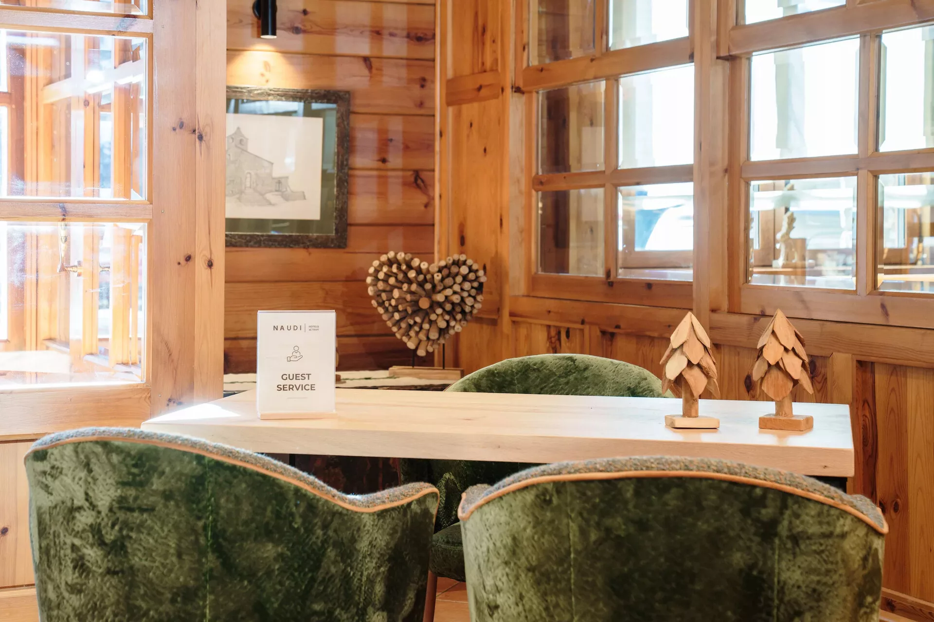 Zona de conserjería con butacas de terciopelo verde y señal Guest Service, Hotel Naudi Boutique